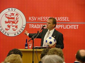 Jens Rose mit Zeigefinger auf KSV-Logo